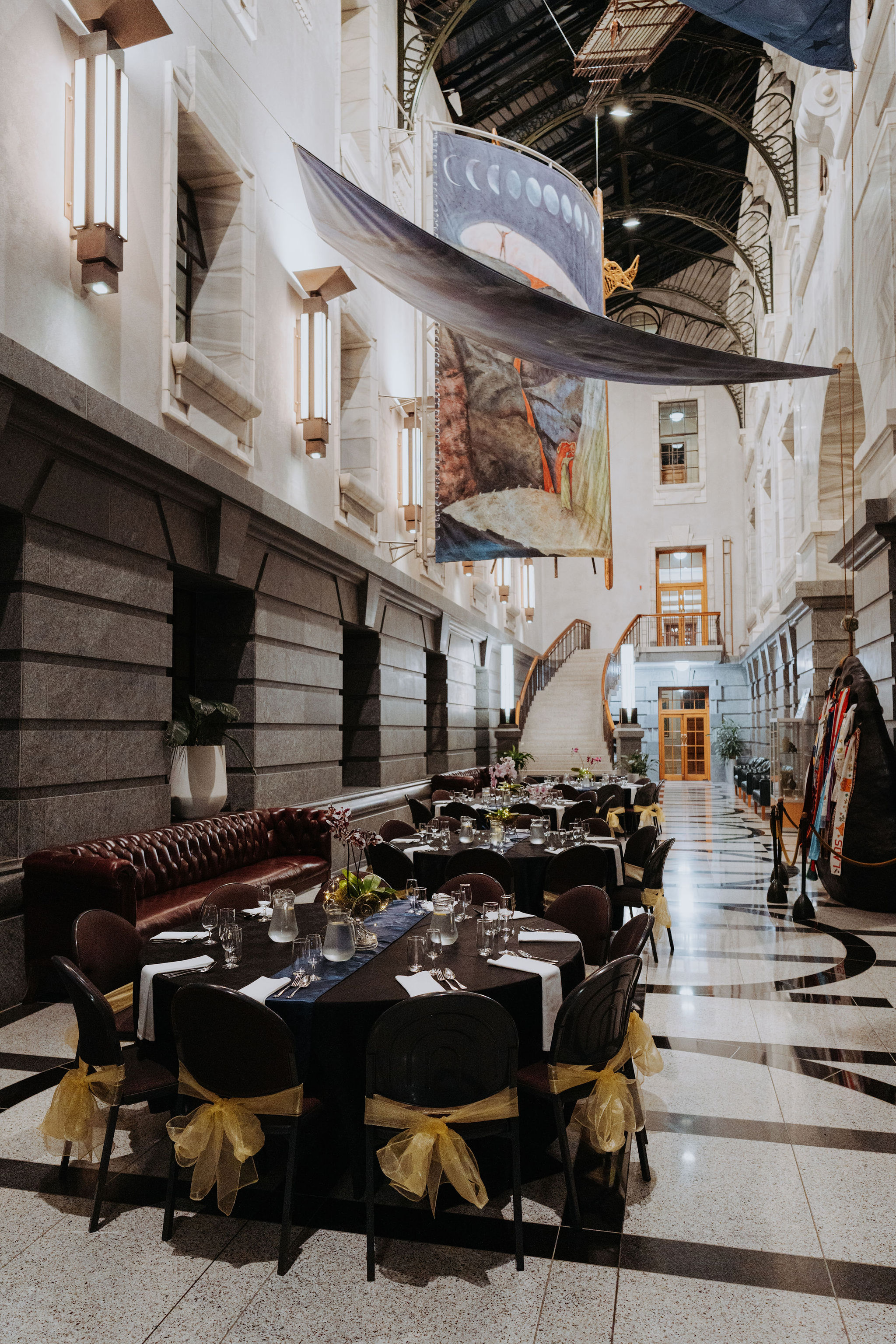 photo of table setup for dinner in Galleria space. Large hanging artwork can be seen suspended above the table.