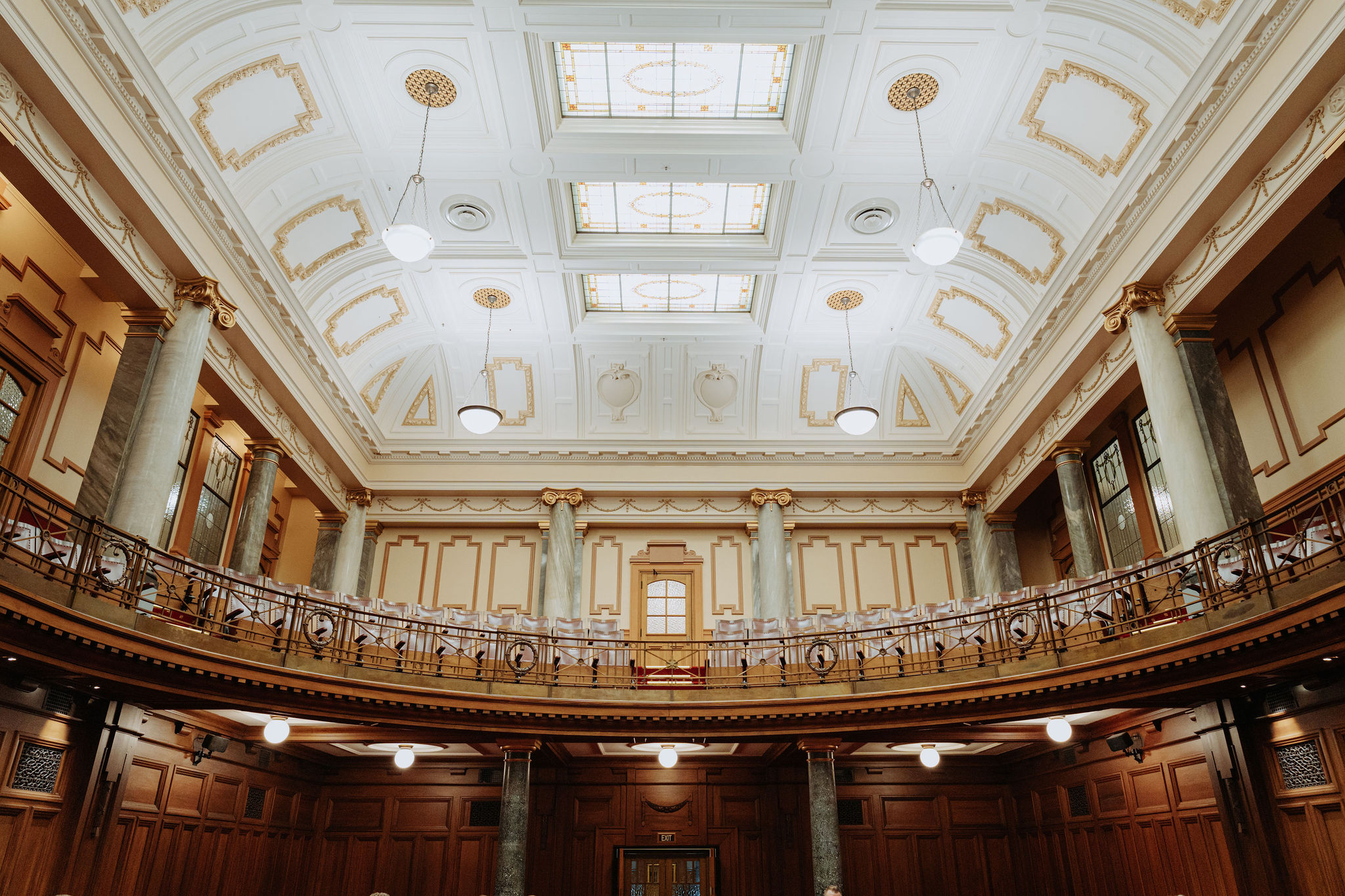 wide photo of the Leglislative Council Chamber showing balcony level ornate ceiling