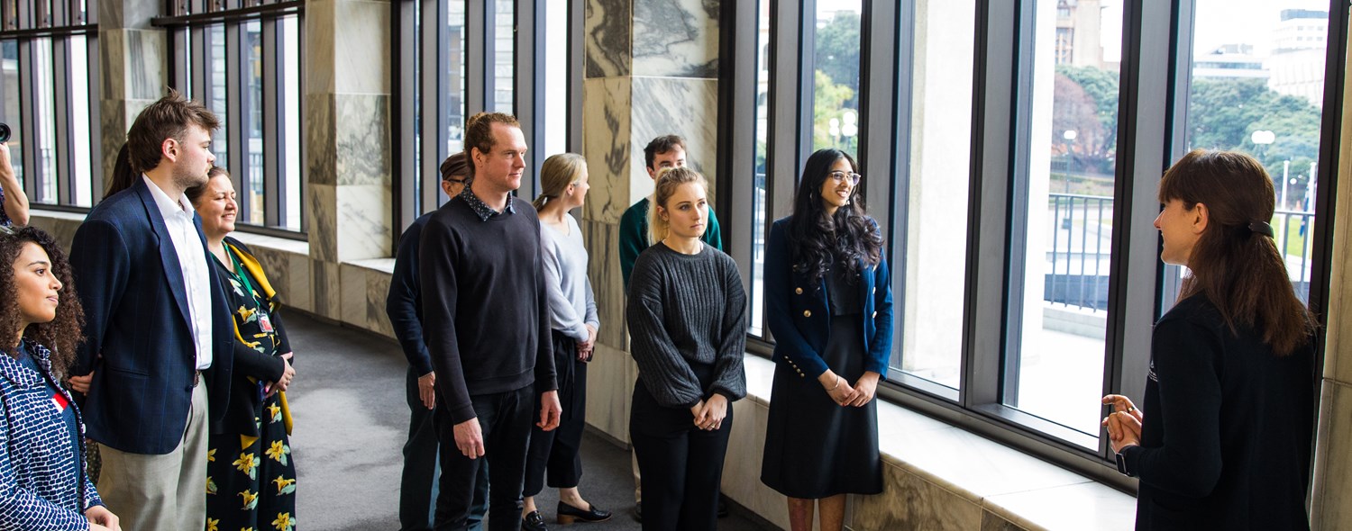 photo showing a mixed group of people listening to a tour guide speak