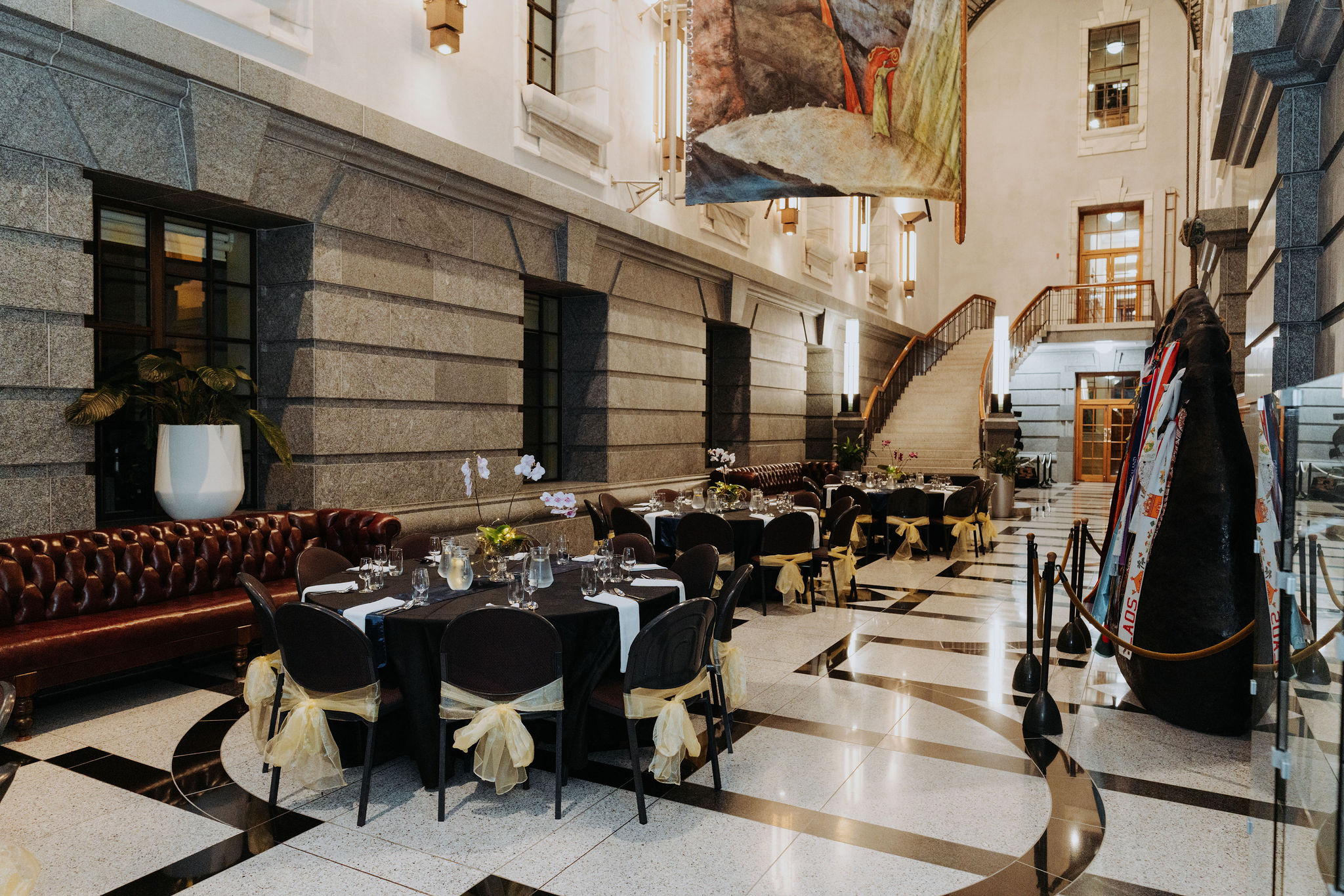 wide photo showing multiple tables setup for dinner in Galleria. Long leather couches can be seen behind the tables.