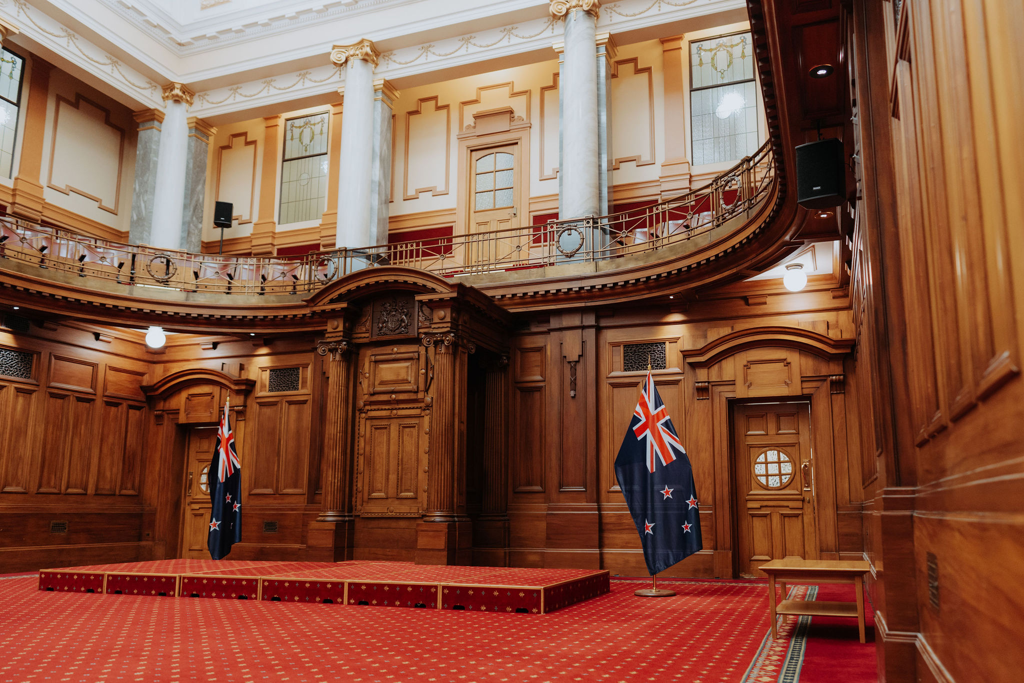 photo of Leglislative Council Chamber showing small stage with NZ flags either side