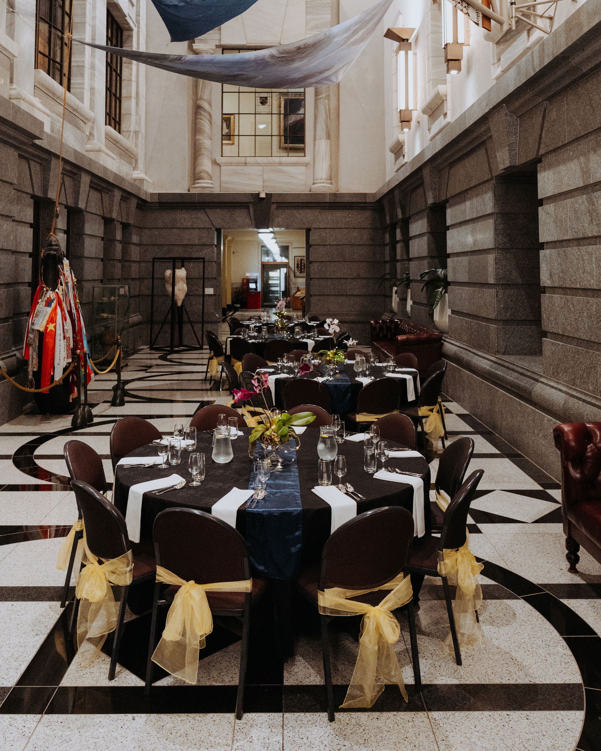 photo of multiple circular tables setup for dinner in Galleria with a floral arrangement centrepiece